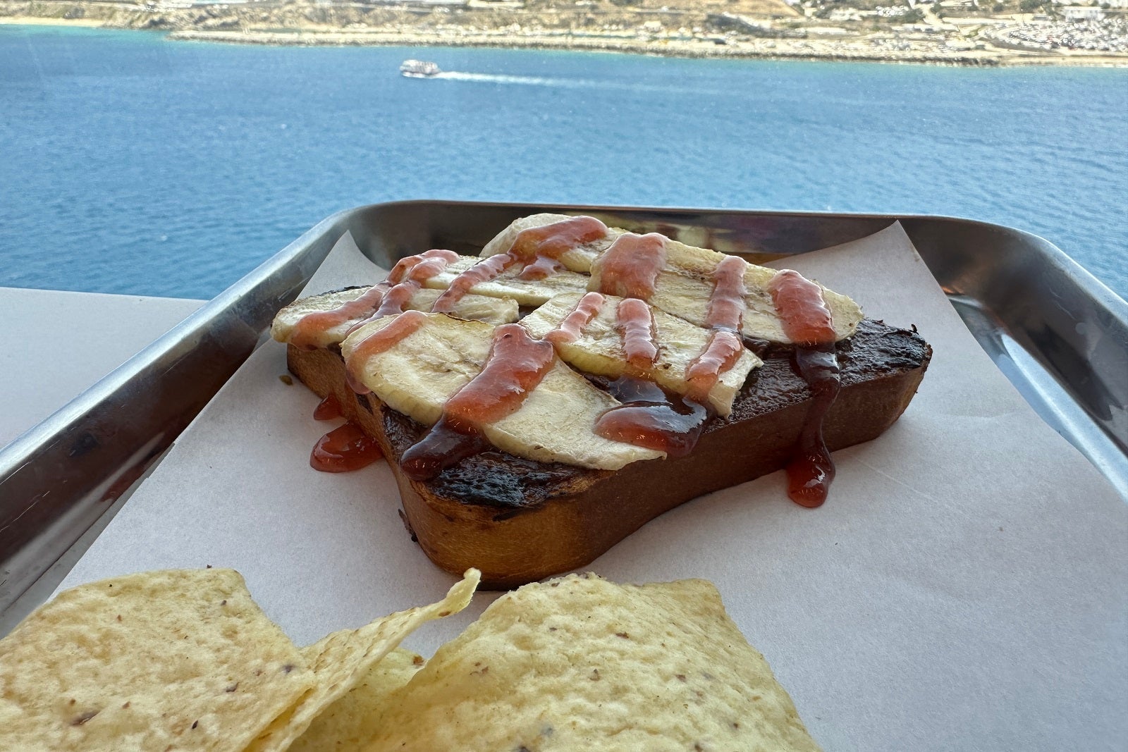 A tray with a sandwich and chips overlooking the ocean
