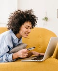Woman using a laptop laying on couch