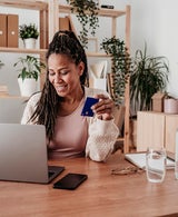 Woman using a laptop while holding a credit card