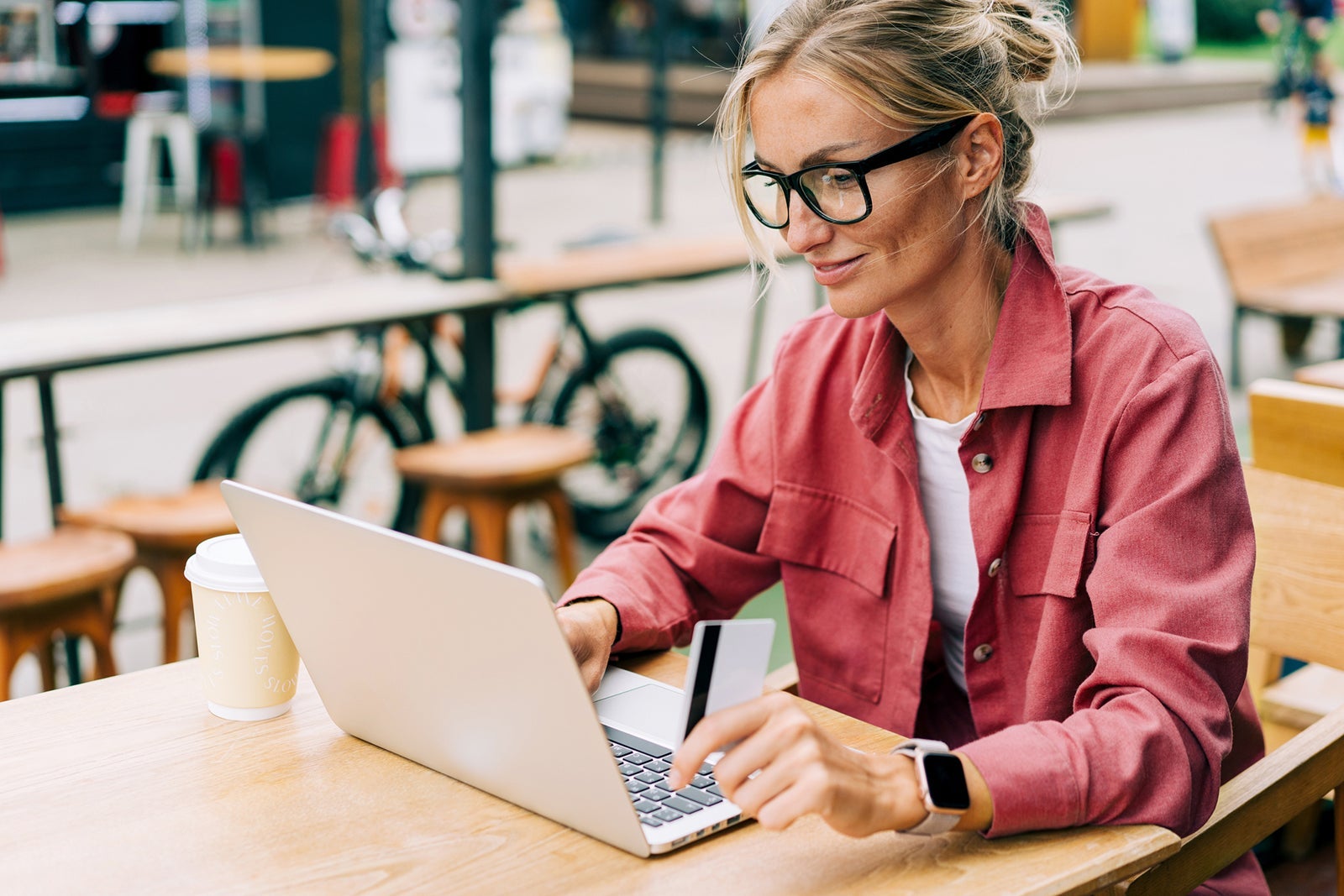 When to get the Amex Business Platinum vs. the Amex Platinum Young caucasian business woman sitting in a cafe working on a laptop.