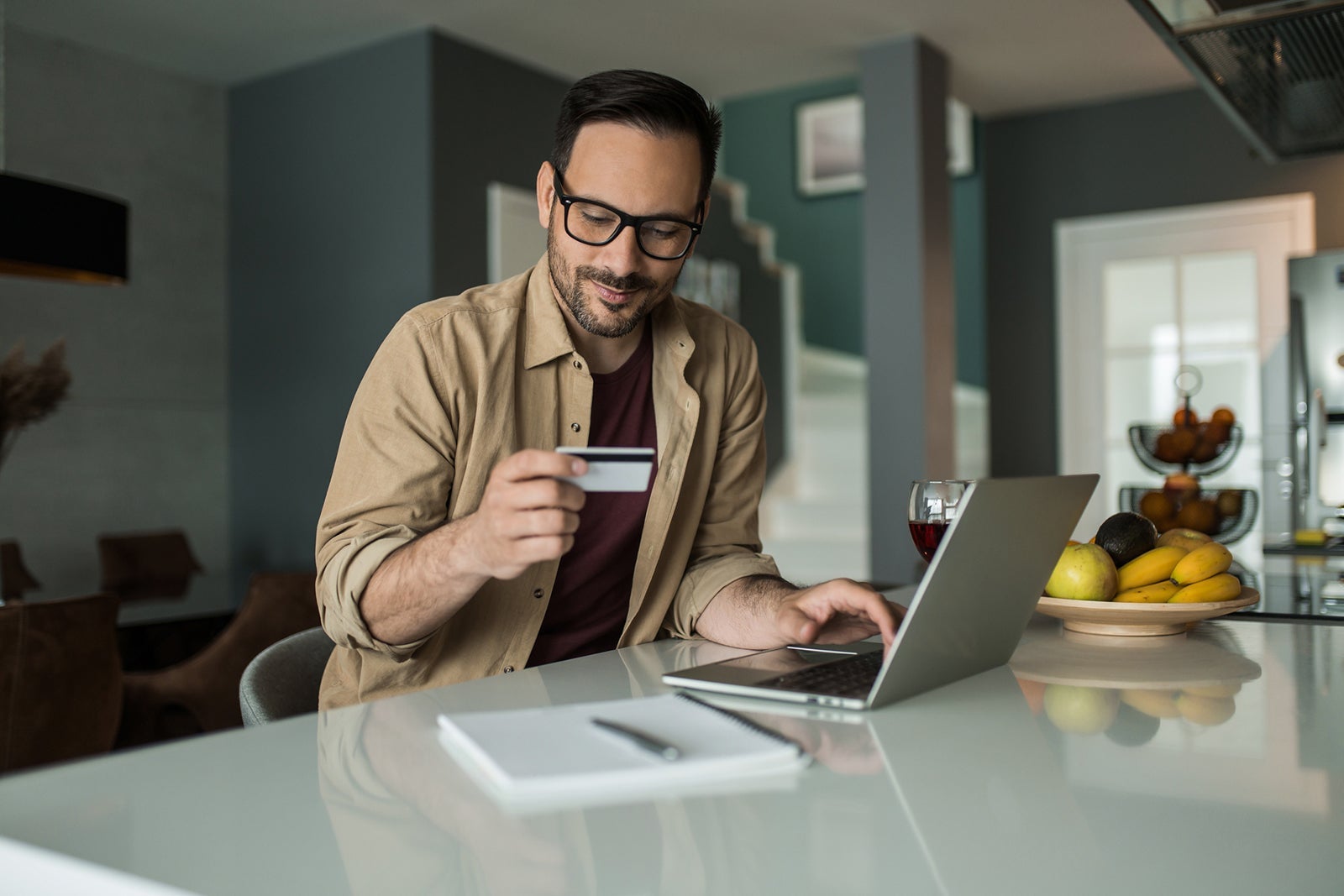 Man looking at credit card while typing on a laptop