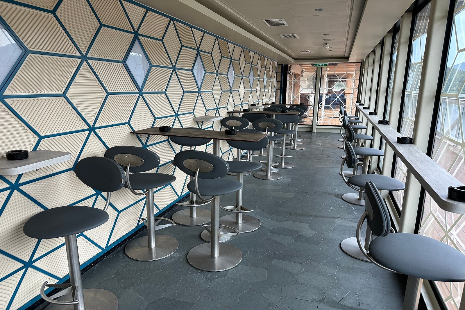 An enclosed smoking area with tables and stools on a cruise ship