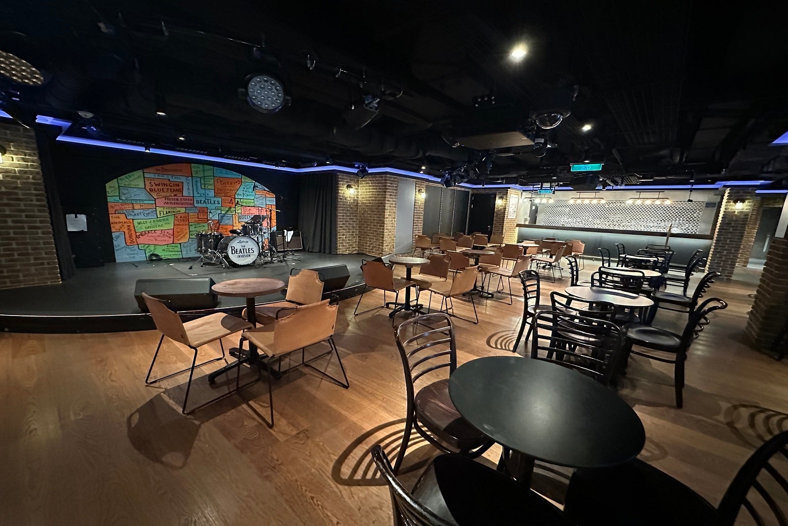 A cavernous looking music lounge on a cruise ship with tables, chairs, and a stage with a drum set that says "Beatles"