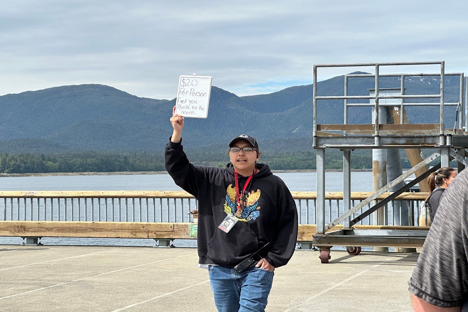 A man holding a sign advertising $20 rides back to a cruise ship from port
