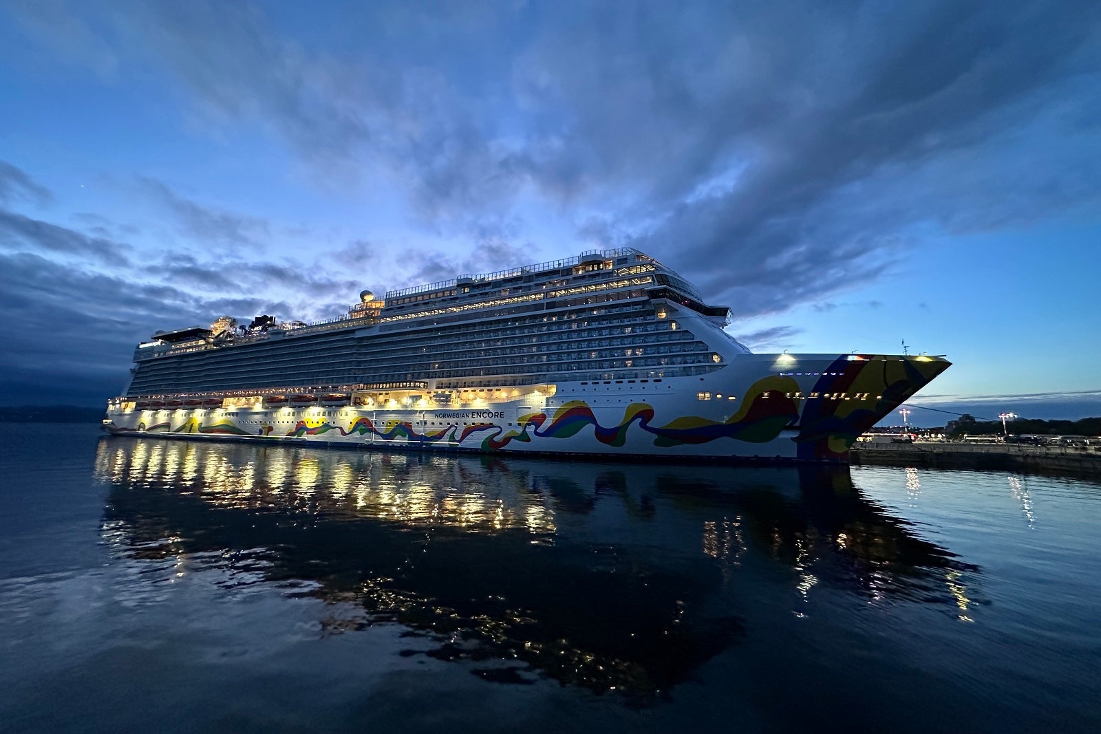 A cruise ship just before sunset with its lights lit up inside