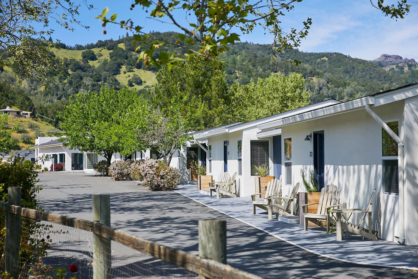 long white building with chairs outside doors sitting in foothills of green hills