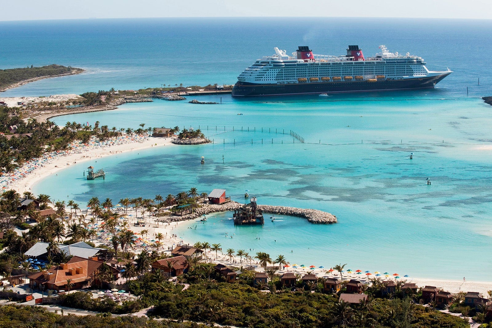 A cruise ship docked at an island surrounded by turquoise water