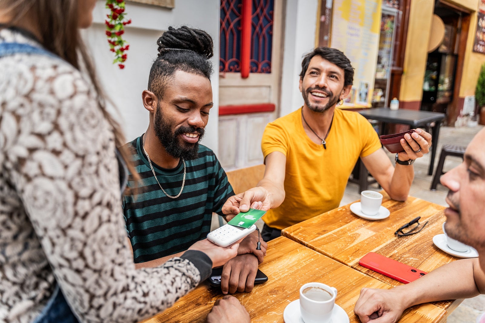 LGBTQIA+ friends paying with credit card at coffee shop