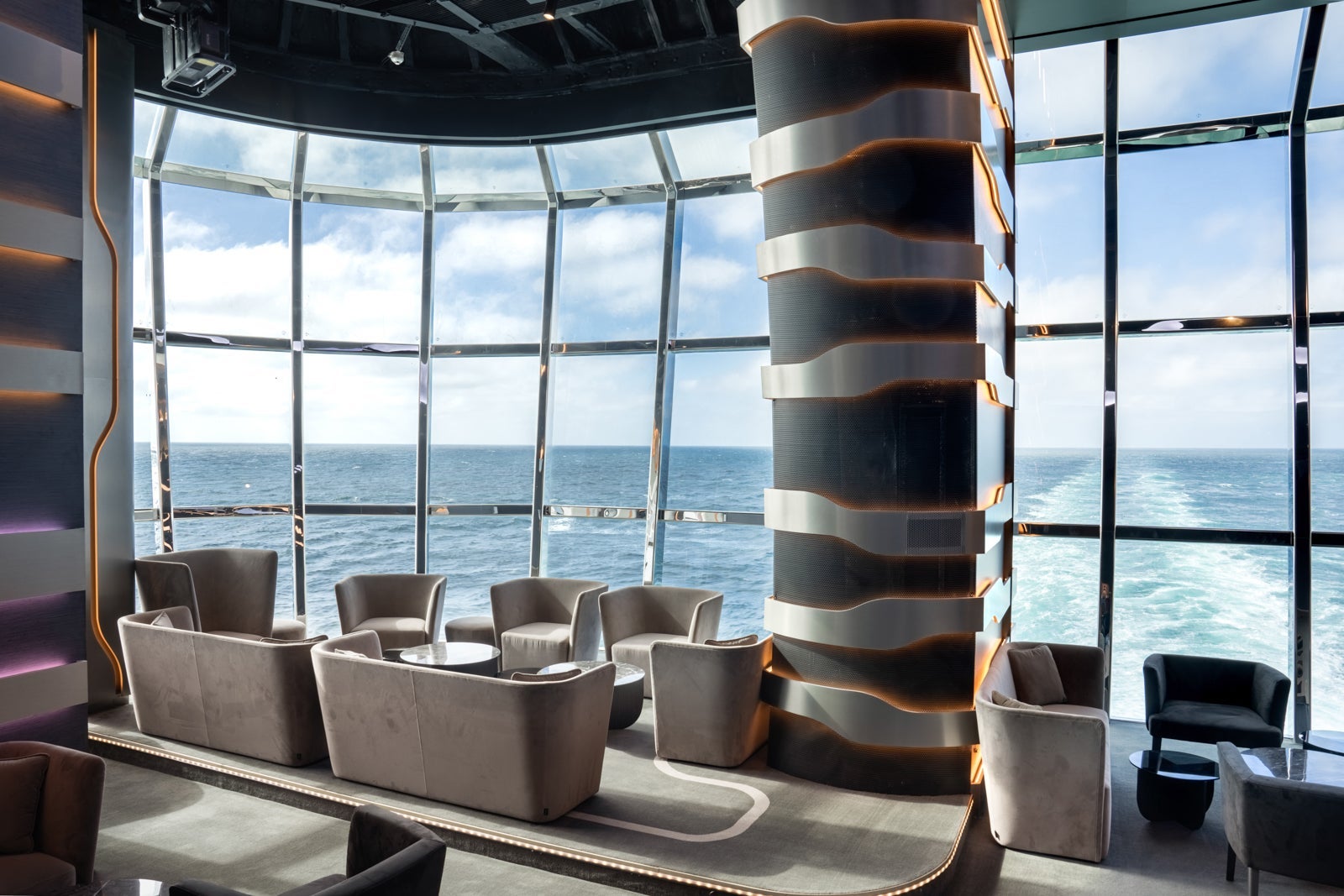 A lounge with large windows overlooking the ocean on a cruise ship