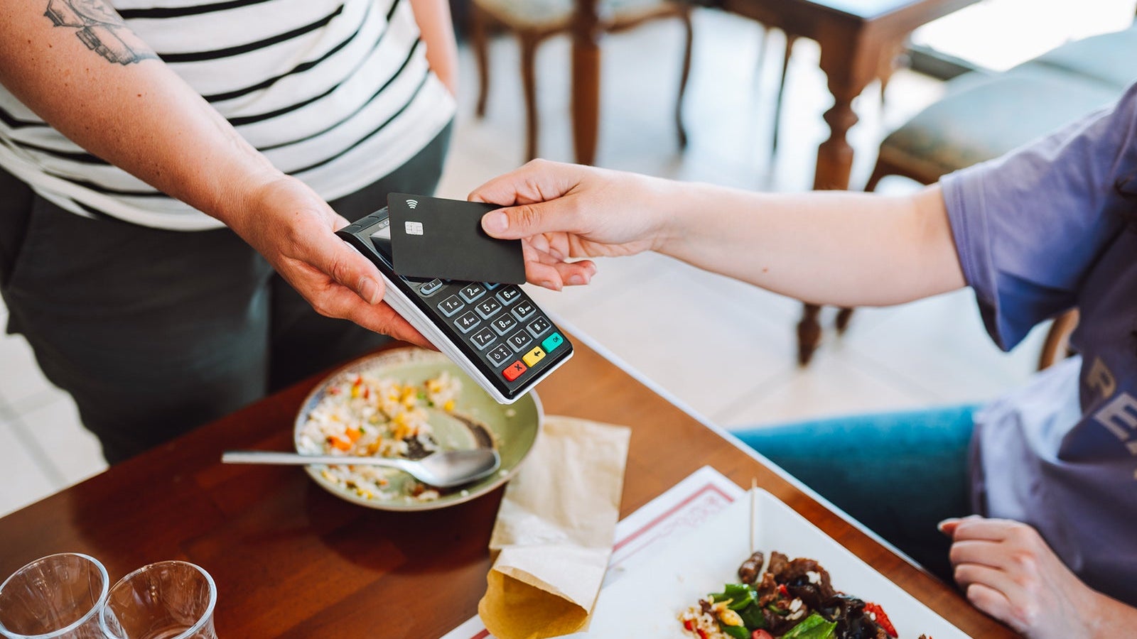 Contactless payment in restaurant. Wireless card reader scanning credit card from customer hand in cafe, high angle view