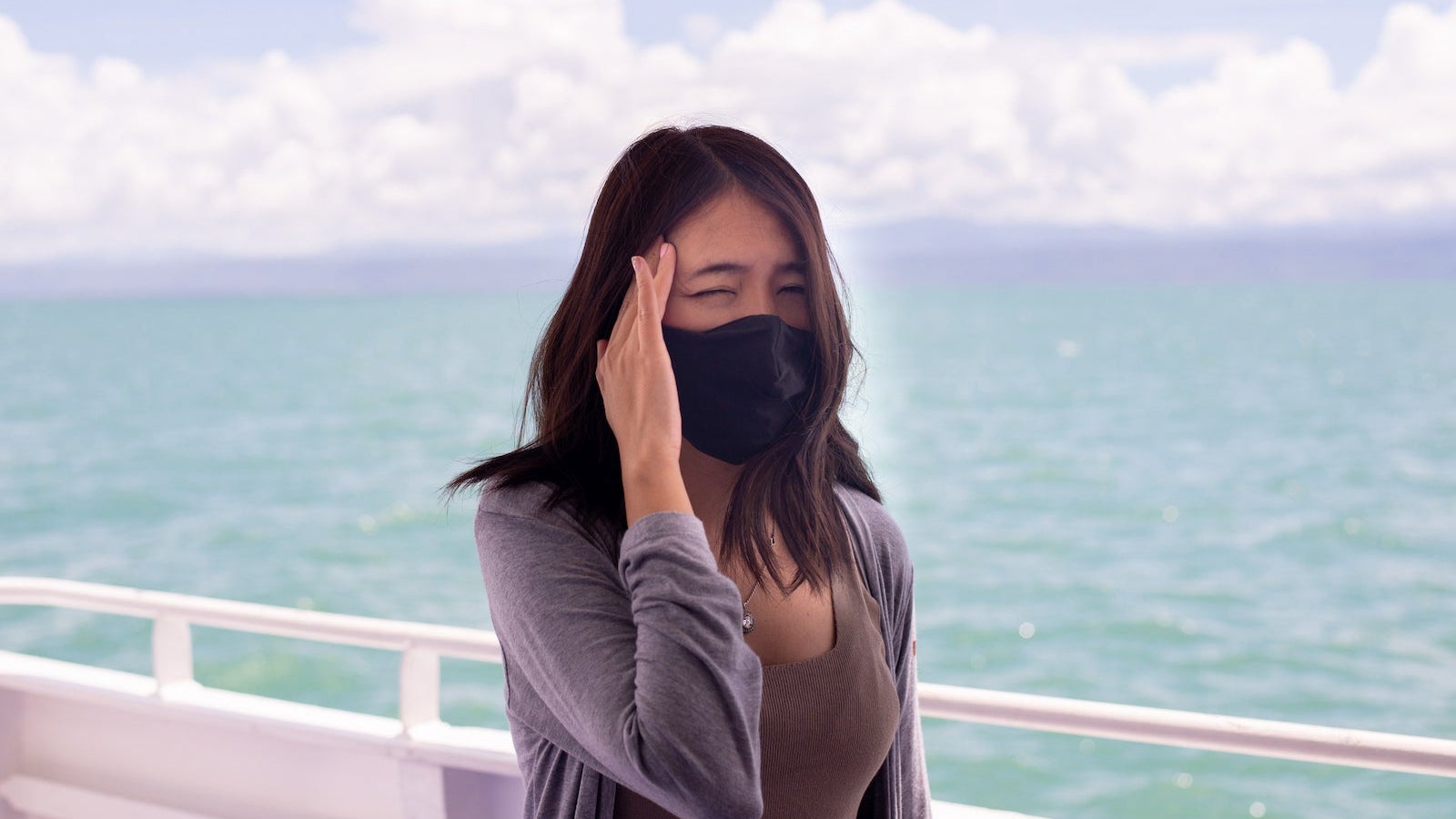 Woman suffering from sea sickness and feeling headache while on boat