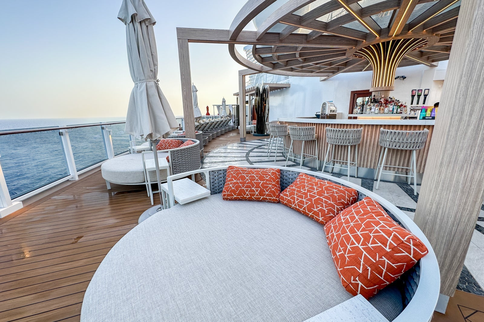 An exclusive cruise ship sun deck with a bar, umbrellas and round loungers with pillows