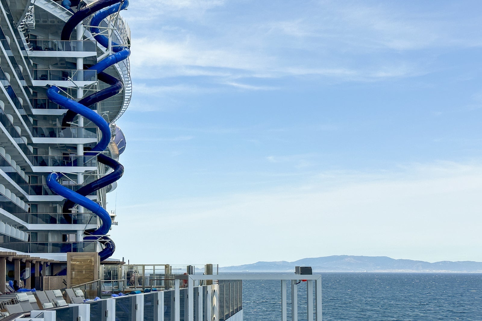 Side of a cruise ship with two twisty slides and blue sky in the background