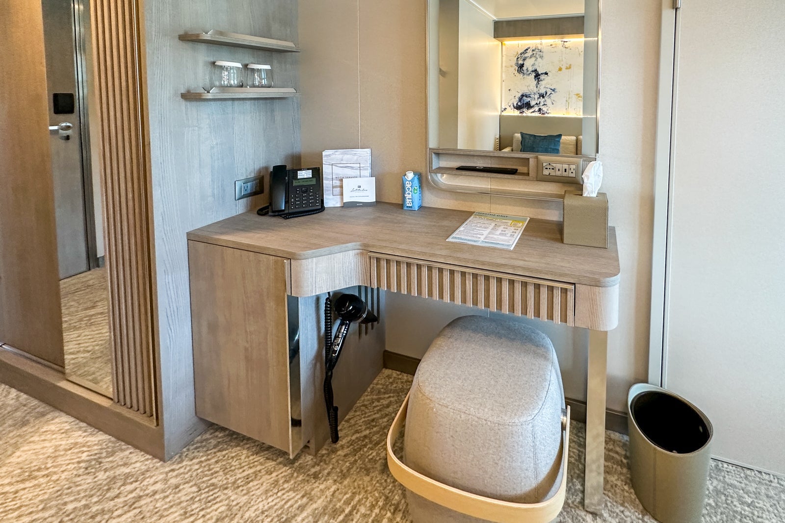 A cruise ship cabin vanity with a stool and mirror