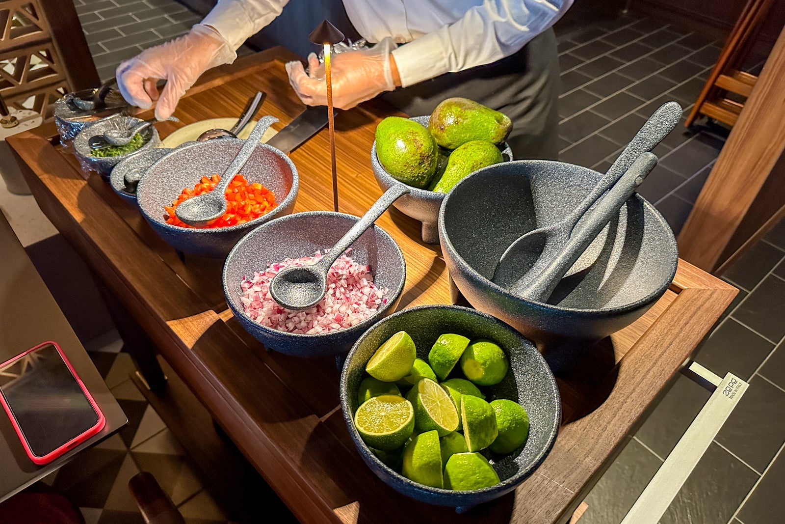 A crew member on a ship making tableside guacamole in a Mexican restaurant
