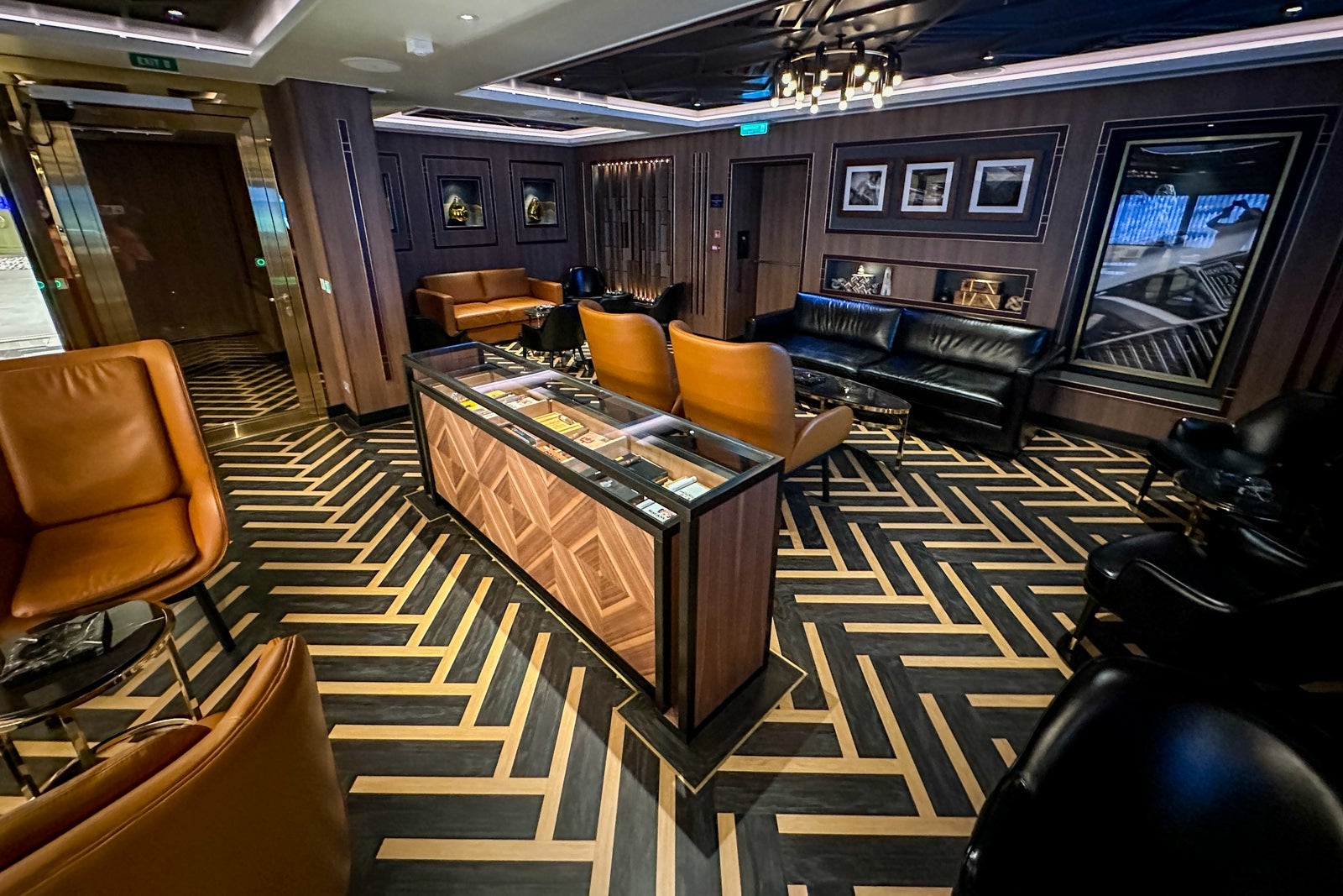 A cigar bar with chevron-patterned flooring, a cigar case and leather seating on a cruise ship