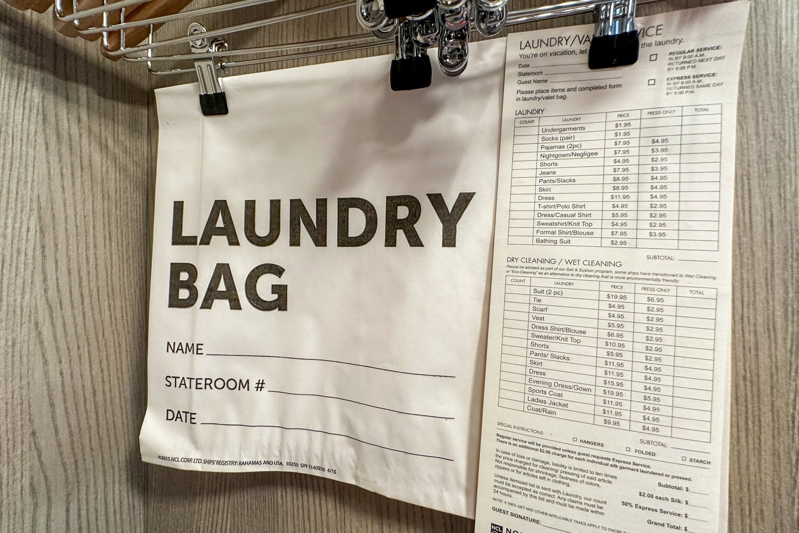 A closet hanger holding a laundry bag and a price list for laundry, pressing and dry-cleaning on a cruise ship