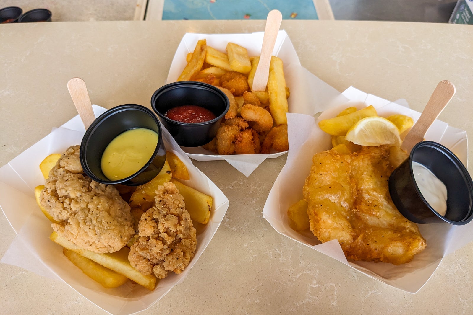 Fried chicken, fish and shrimp with French fries in white paper baskets
