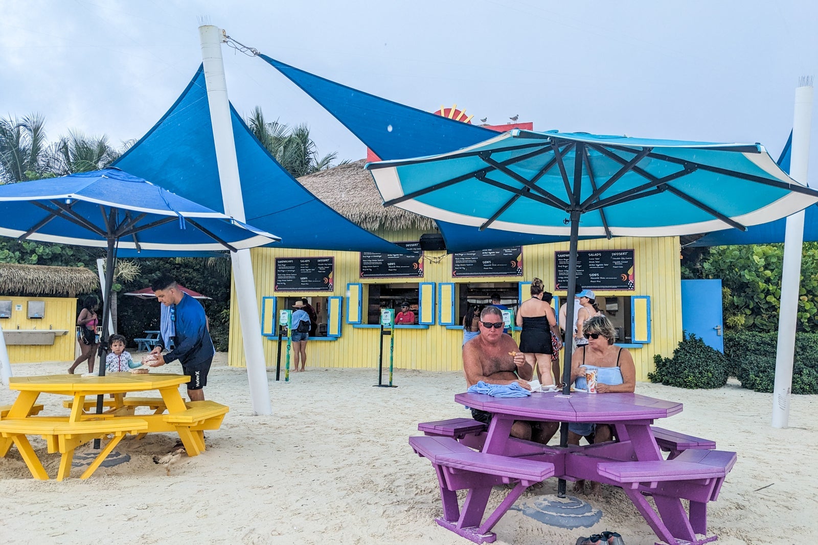 Yellow snack shack with ordering windows and picnic tables in front