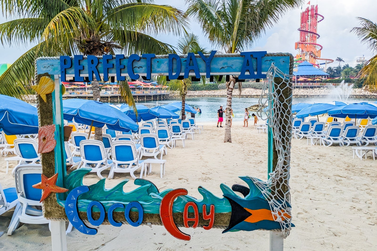 Sign reading Perfect Day at CocoCay framing view of beach and lounge chairs