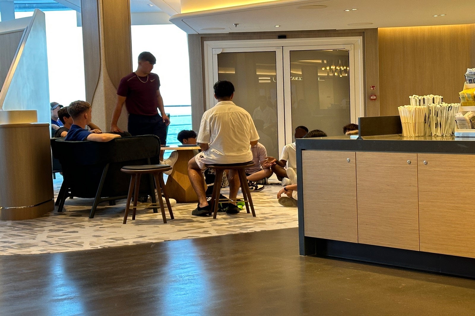 A group of teenagers crowded around in a lounge on a cruise ship