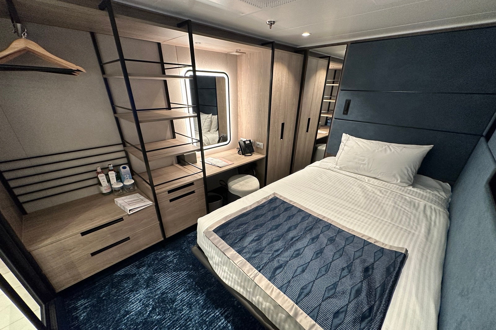 A small cruise cabin with a full sized bed, a small vanity and a closet