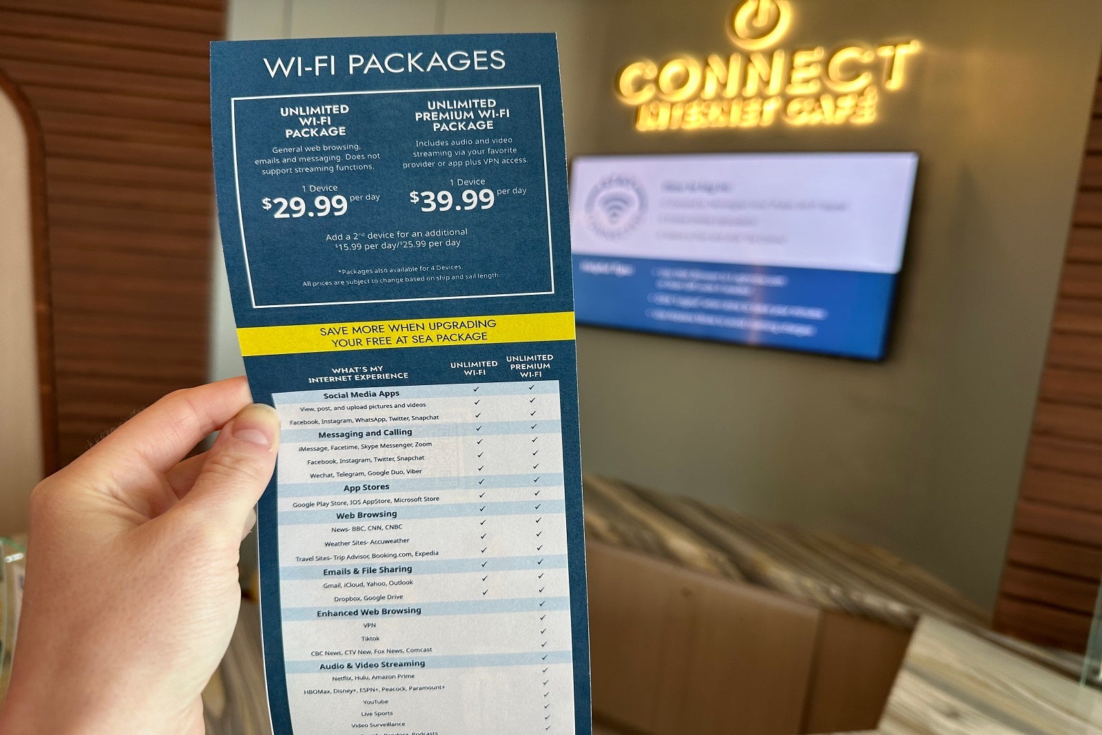 A hand holding a price list for Wi-Fi on a cruise ship