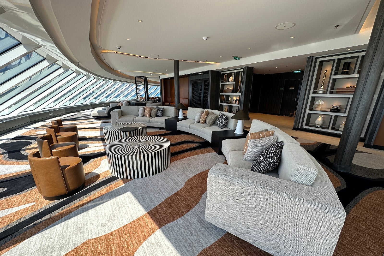 A cruise ship lounge with lots of seating, tables and panoramic windows