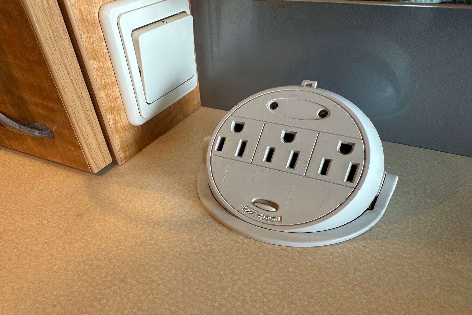 A round plastic base with three electrical outlets on a desktop