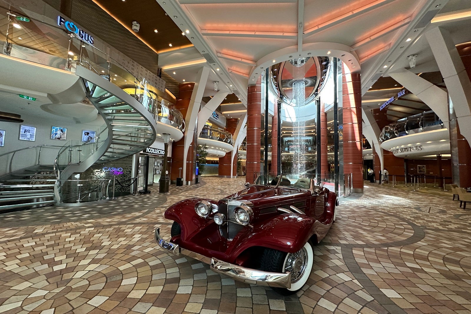 A vintage car parked on an indoor promenade on a cruise ship