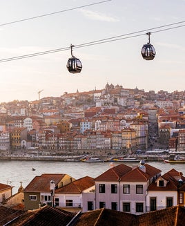 Cable car cabins moving above Porto city and Douro river at sunset, Portugal
