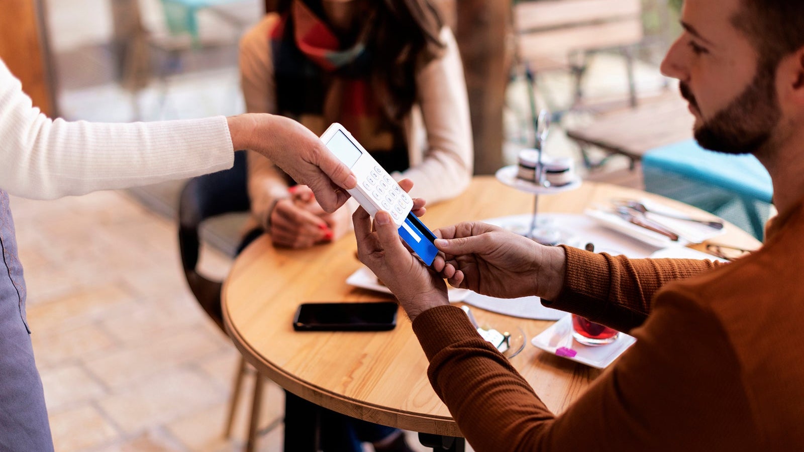 Close-up of a man man paying with card in a cafe