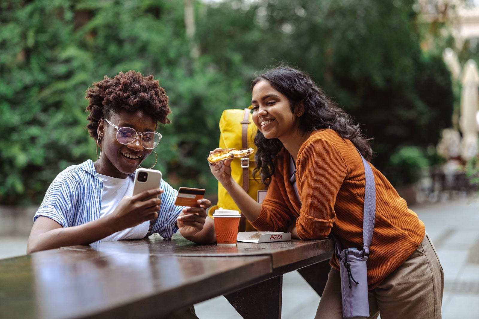 Pair of friends with a credit card eating pizza