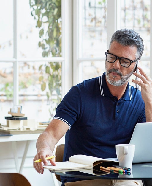 Businessman using mobile phone while writing notes