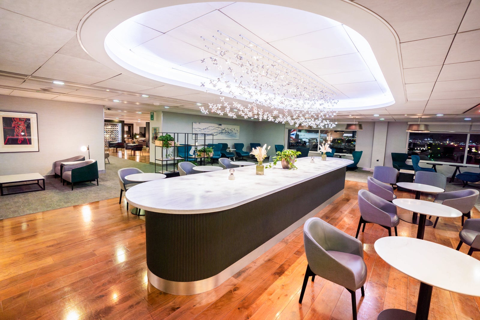 a long table in the middle of a lounge with hardwood floors and lots of seating