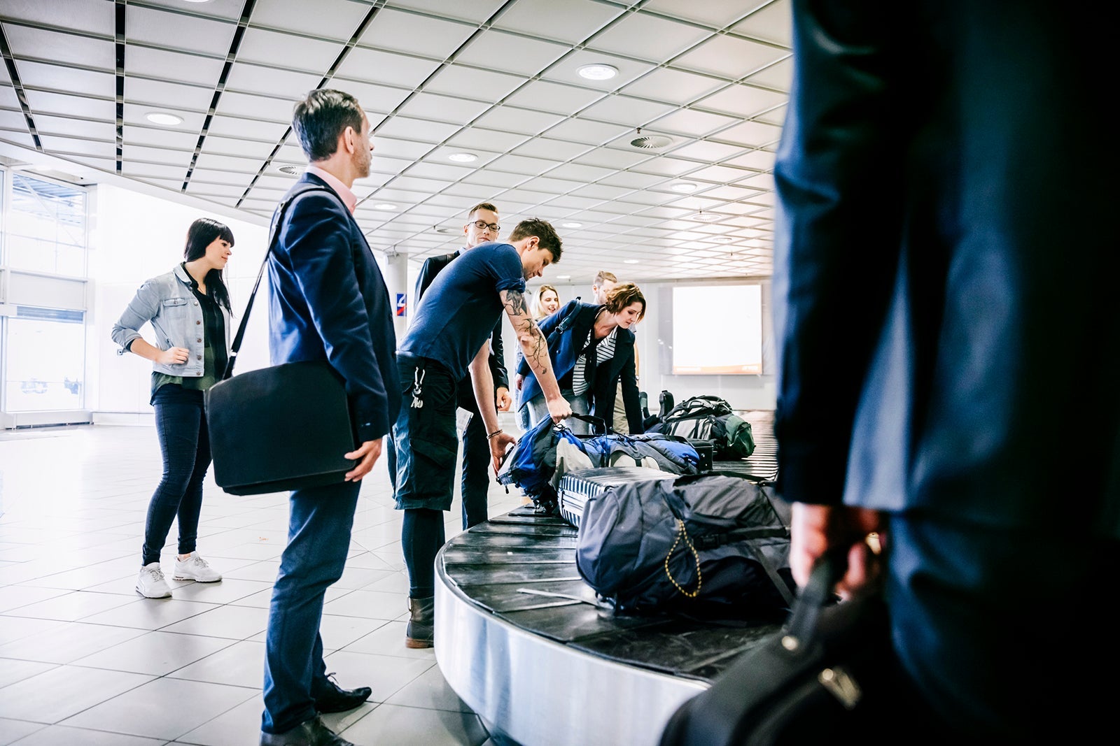 Group of travelers waiting for luggage at carousel