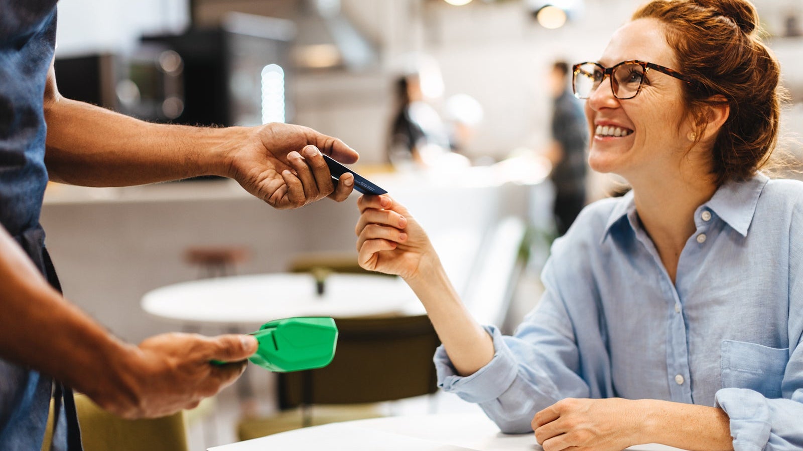 Woman using a credit card to pay for her bill in a coffee shop
