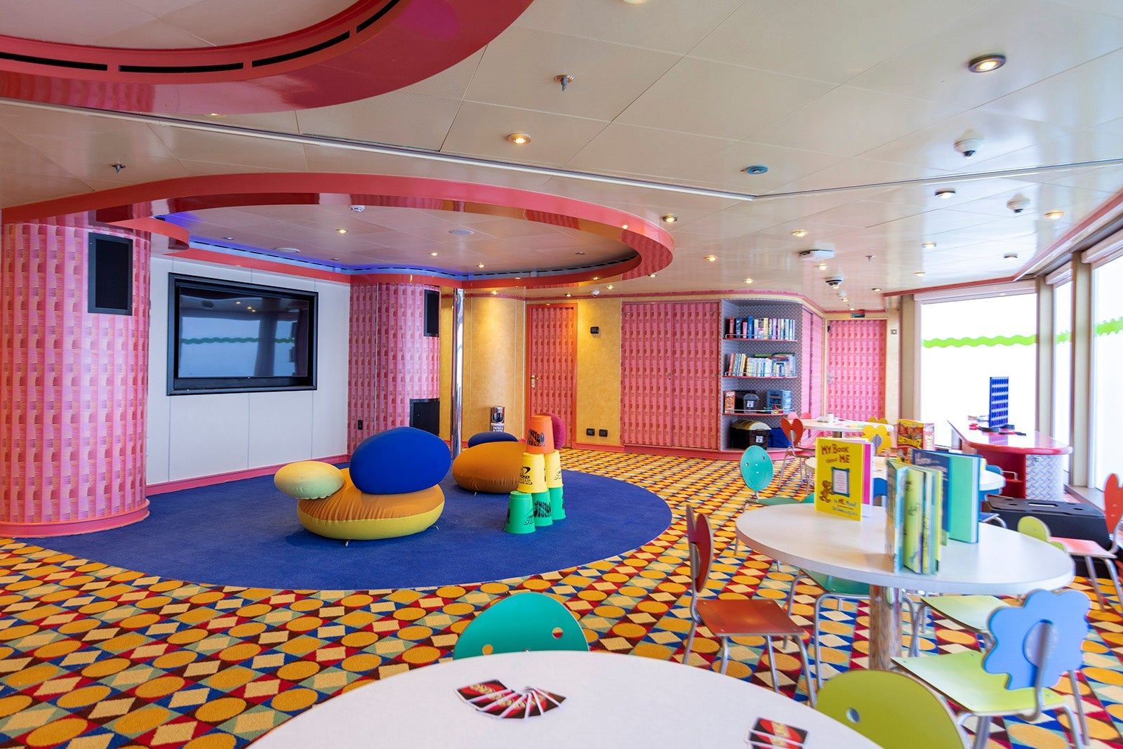 Colorful multipurpose space for kids on a cruise ship with round tables and Dr. Seuss books