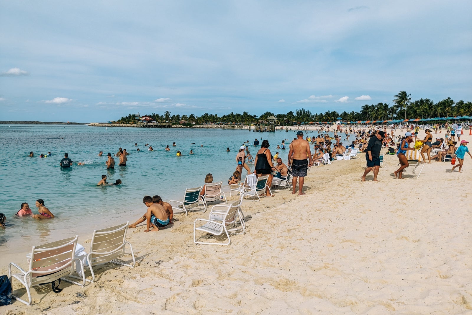 Bahamian beach crowded with families with palm trees in the distance