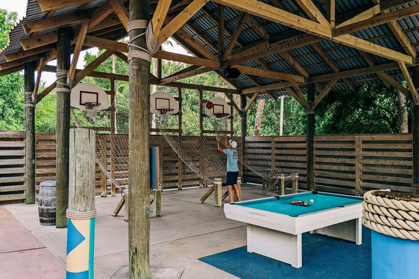 Man playing basketball in open-air wooden structure