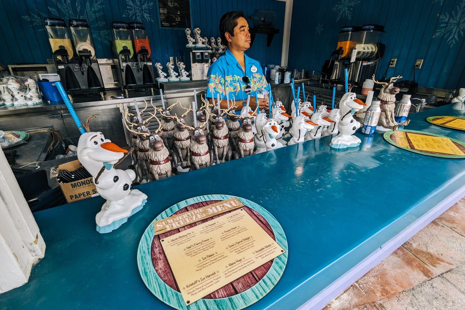 Bartender with Olaf and Sven souvenir drink cups.