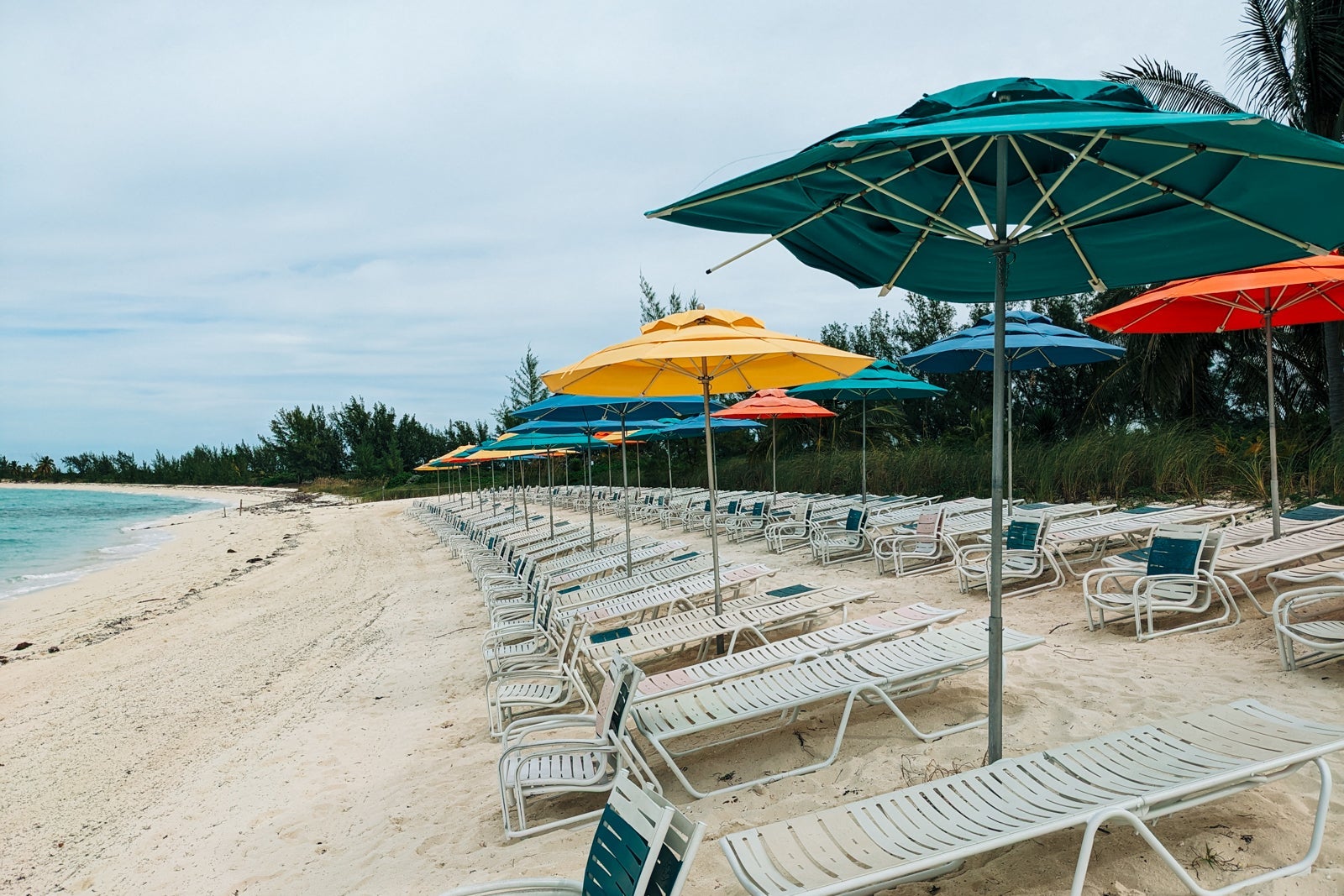 Empty lounge chairs and blue and yellow umbrellas on a Bahamian beach
