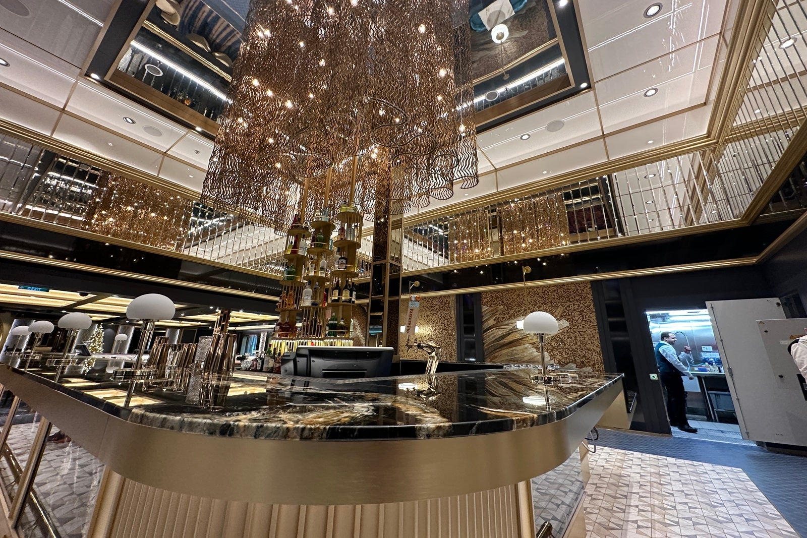 A gold and black bar with an art deco light fixture hanging down from the ceiling above it