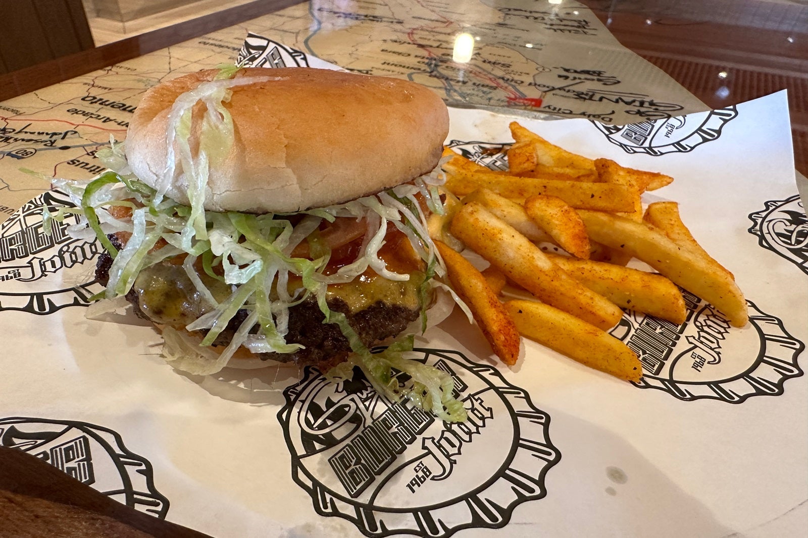 A loaded cheeseburger with a side of fries on a plate on a table