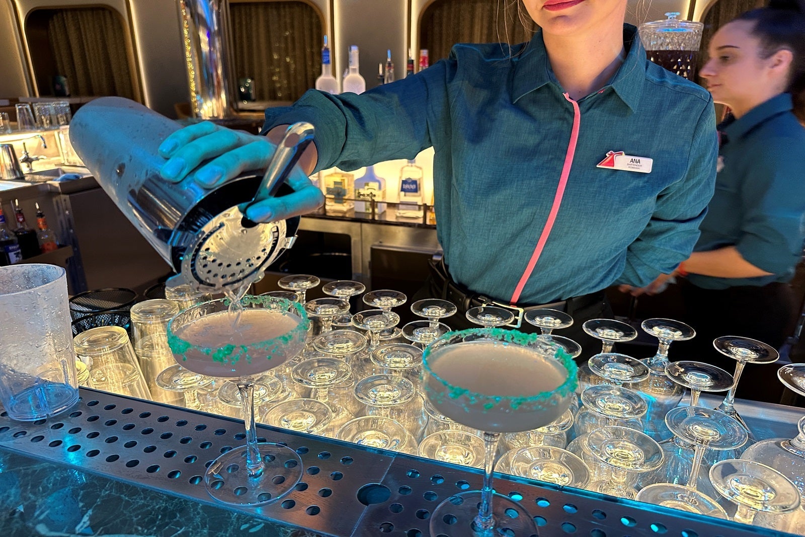 A bartender pours a shaker of alcohol into two glasses rimmed with Pop Rocks