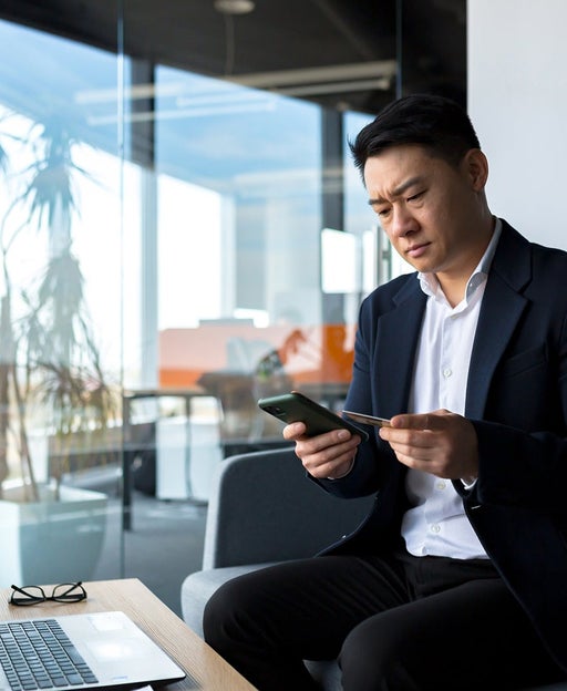 Man looking at his phone in front of a computer