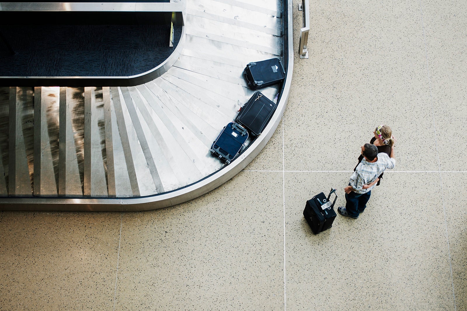 an aerial view of two people standing at a baggage carousel