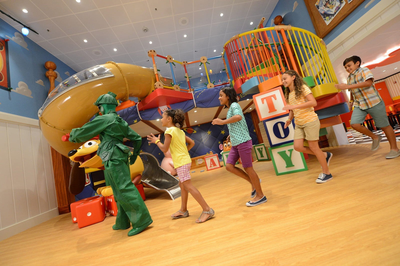 Green army soldier leads kids on a march through the Andy's Room themed playspace on a Disney cruise ship