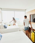 Two people wheeling their suitcases into a hotel room