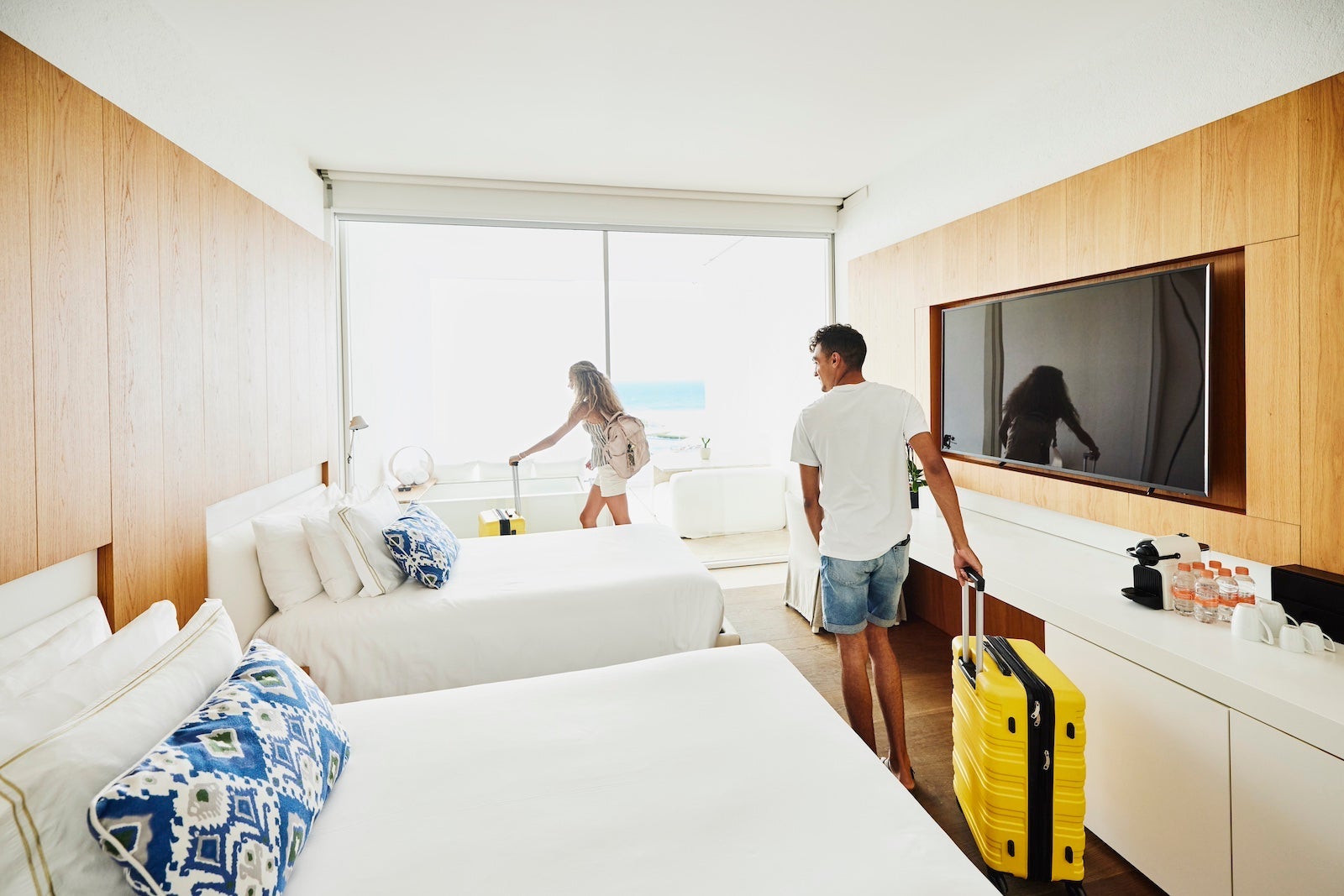 Two people wheeling their suitcases into a hotel room